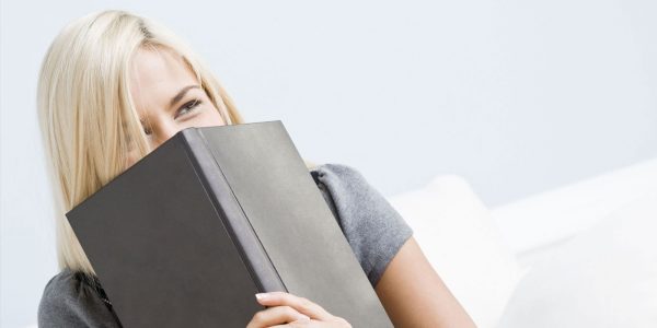 A woman laughing behind a book