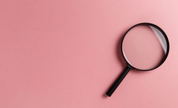 Magnifying glass on pink background. Top view. Flat lay. Copy space. Minimal creative concept. Search concept